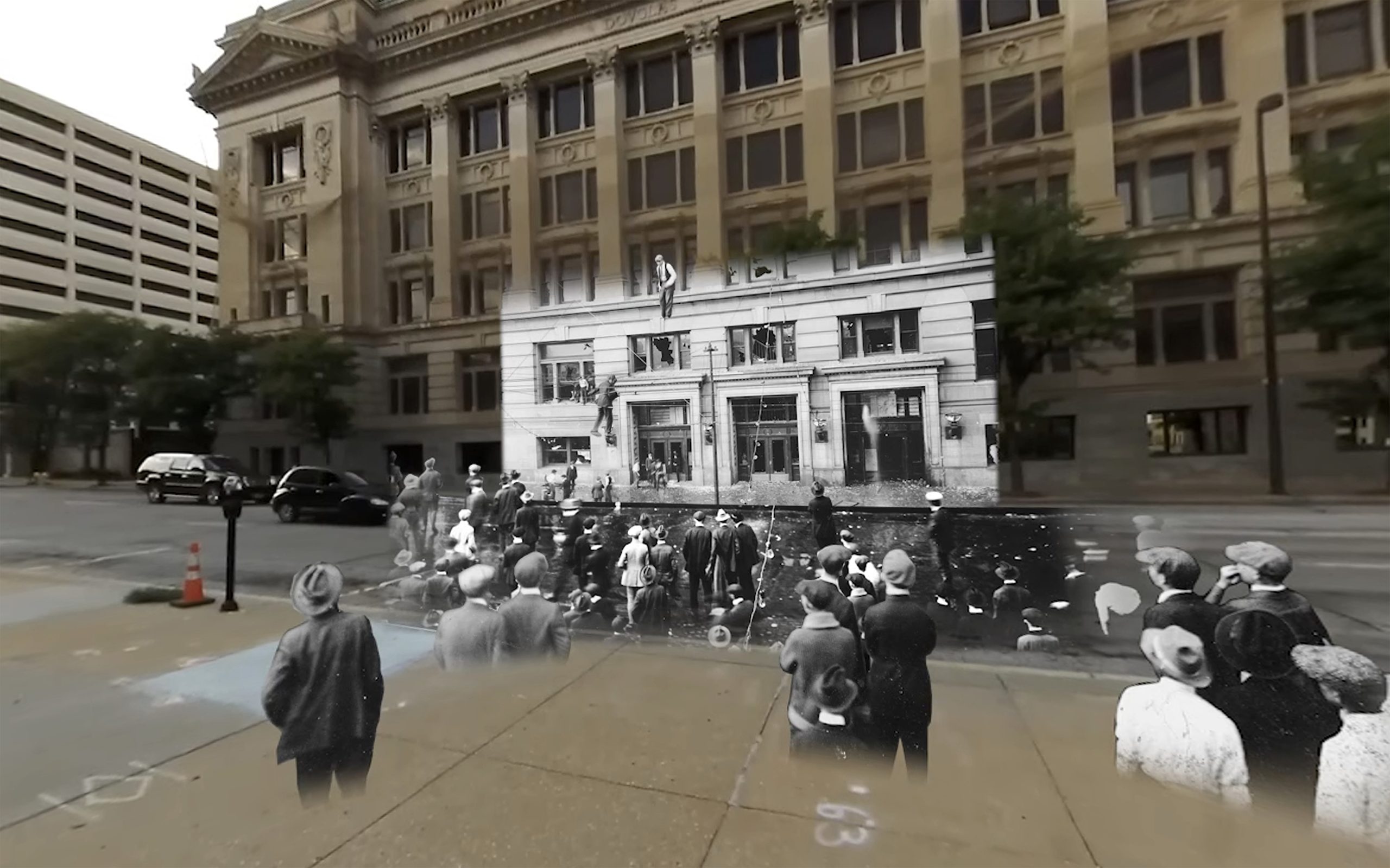 A black and white 1919 photograph of a crowd of white people descending on a courthouse, smashing windows, some climbing the building's facade, is layered on top of a contemporary color photograph of the same building.