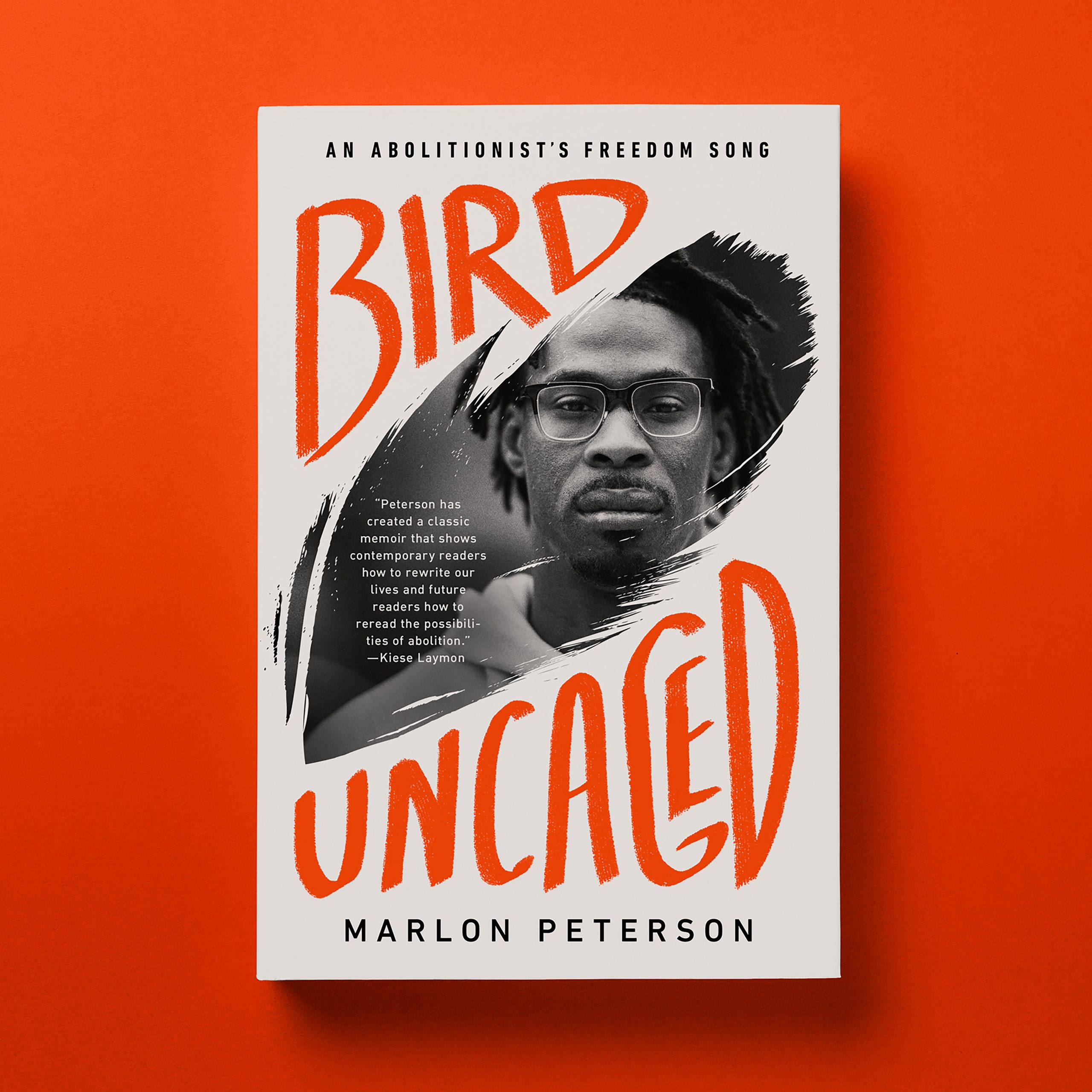 Cover of Marlon Peterson's memoir with the title Bird Uncaged: An Abolitionist's Freedom Song in orange Lettering with a photographic cutout in the shape of a feather with the face of Marlon Peterson in it. Peterson, a Black man, wears glasses and has a thoughtful expression.