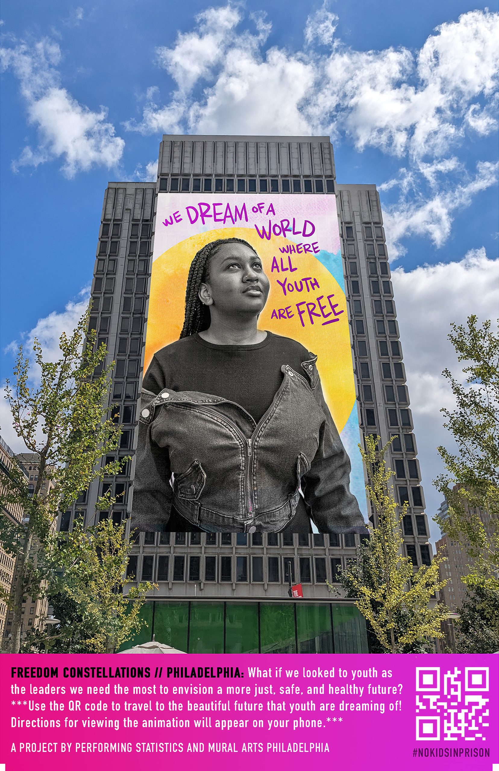 A banner hanging from a tall building shows a Black youth looking to the sky in front of a yellow sun, with the words 